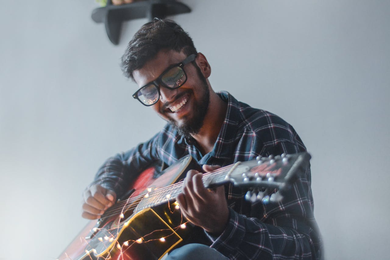 Mann spielt Gitarre in der Wohnung Vorteile von Akustikpaneelen für Musiker daheim