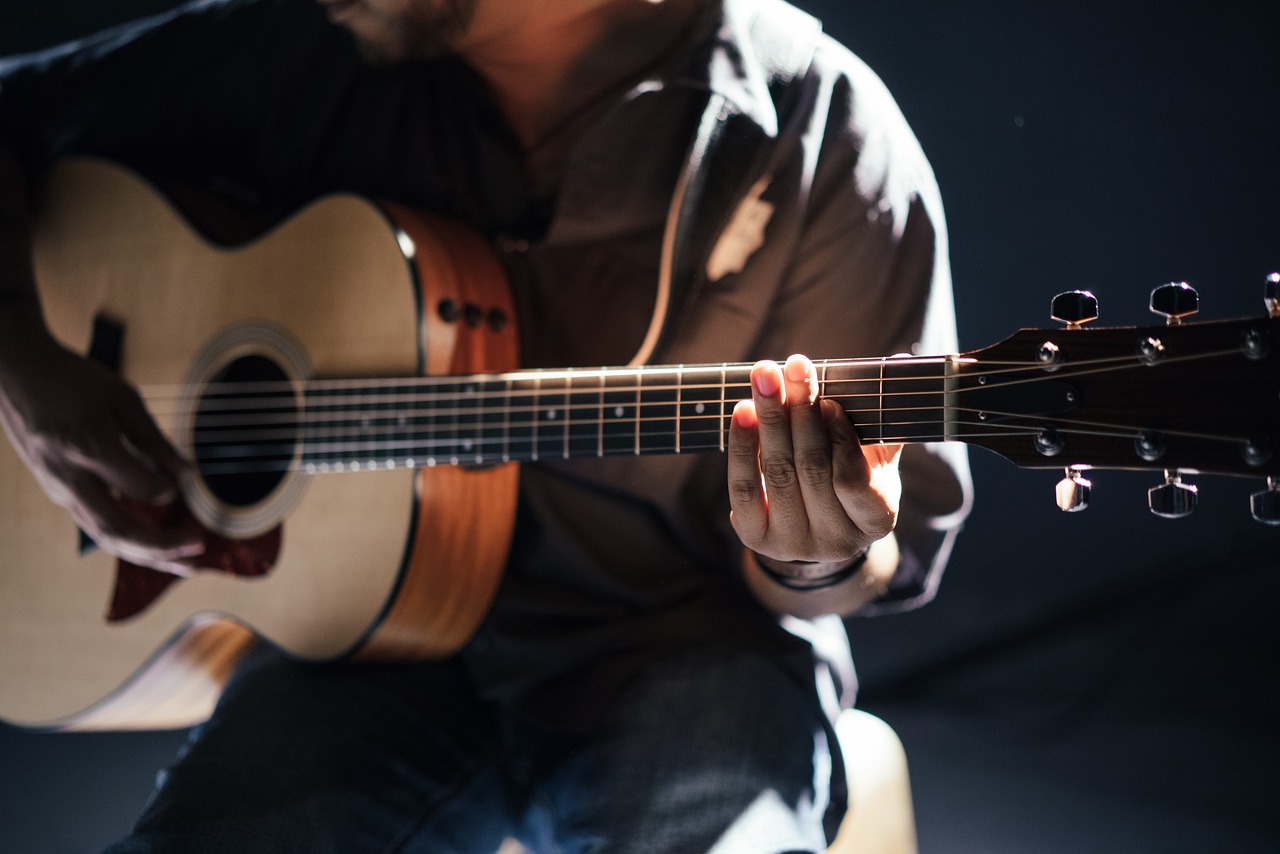Mann spielt akustische Gitarre Akustik vs. E-Gitarre Die beste musikalische Begleitung für besondere Anlässe